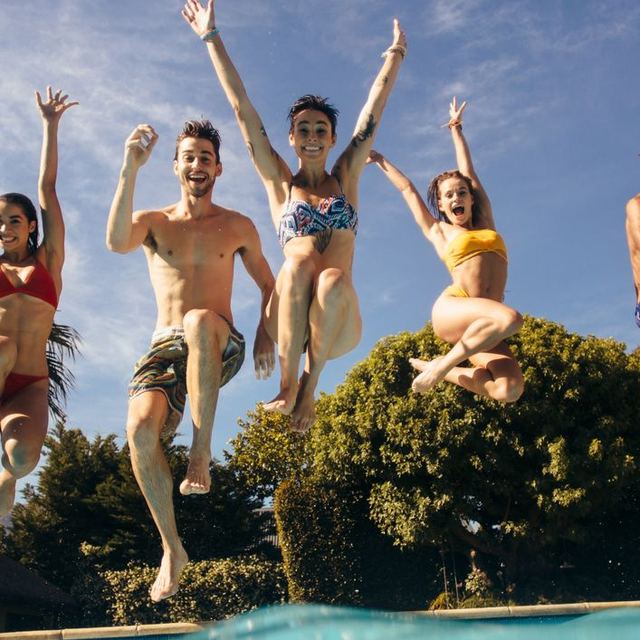 Friends jumping into a backyard pool in Gilbert, Arizona