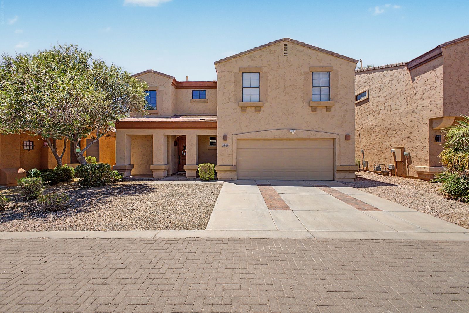 Front exterior of the two-story home with a two-car garage and desert landscaping