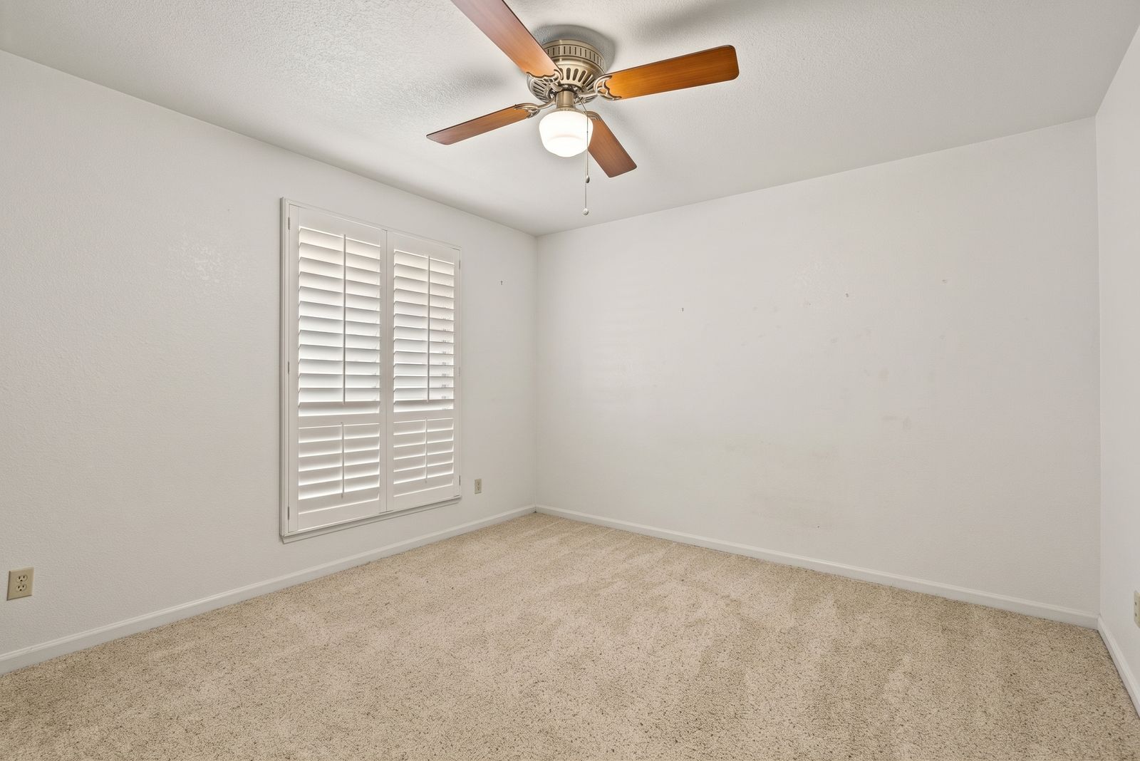 Bedroom with carpet, ceiling fan and plantation shutters