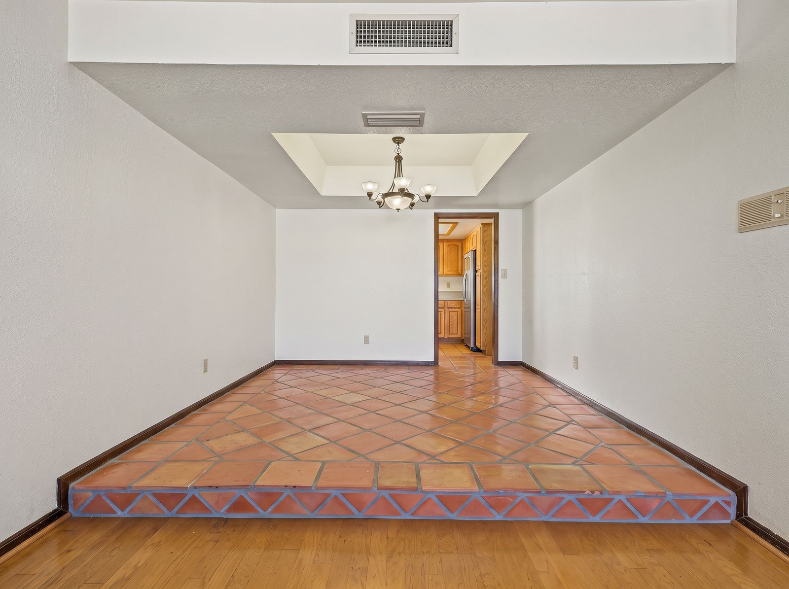 Formal dining room with a raised Saltillo tile platform and chandelier