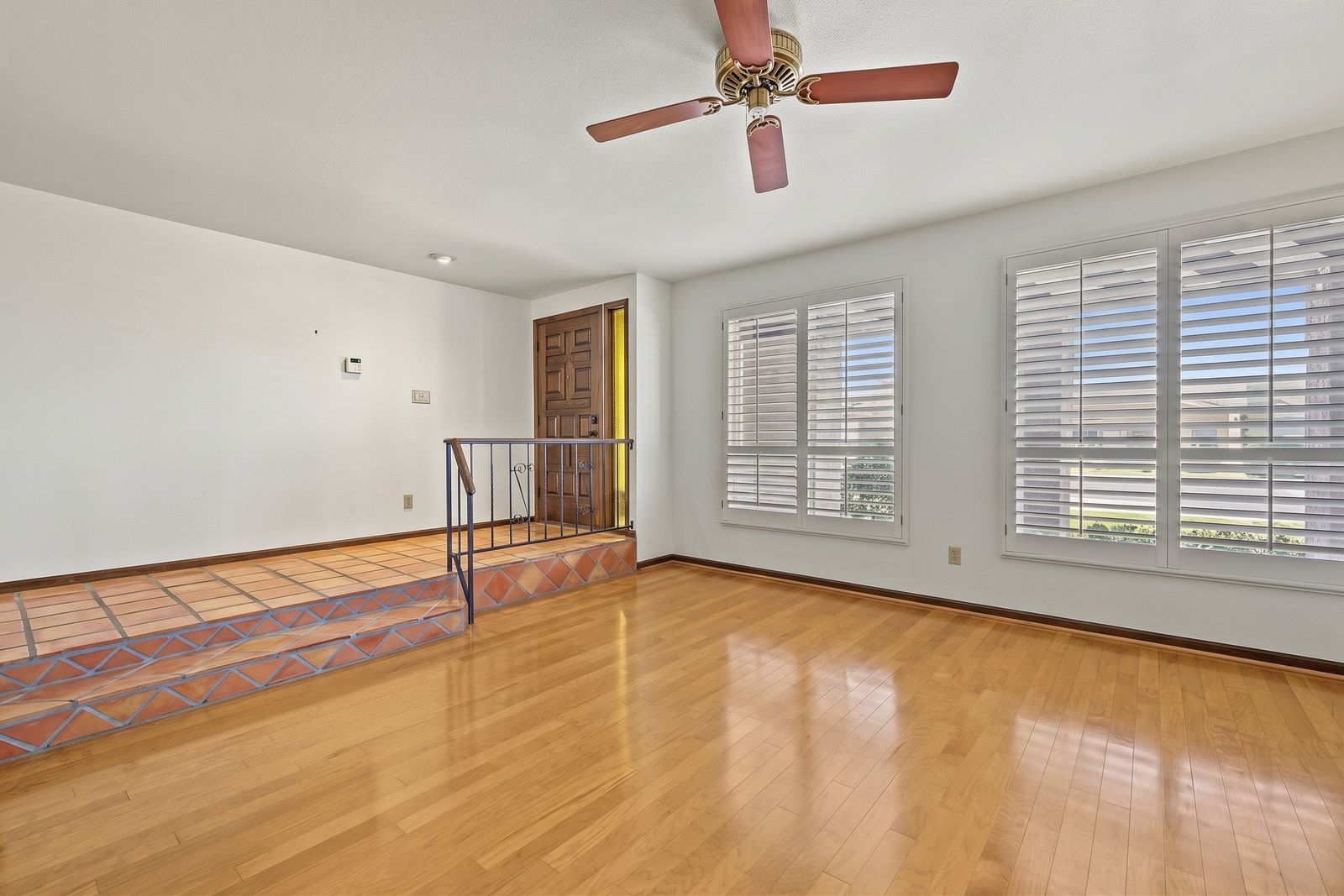 Living room with wood floors, plantation shutters and a tiled entry step