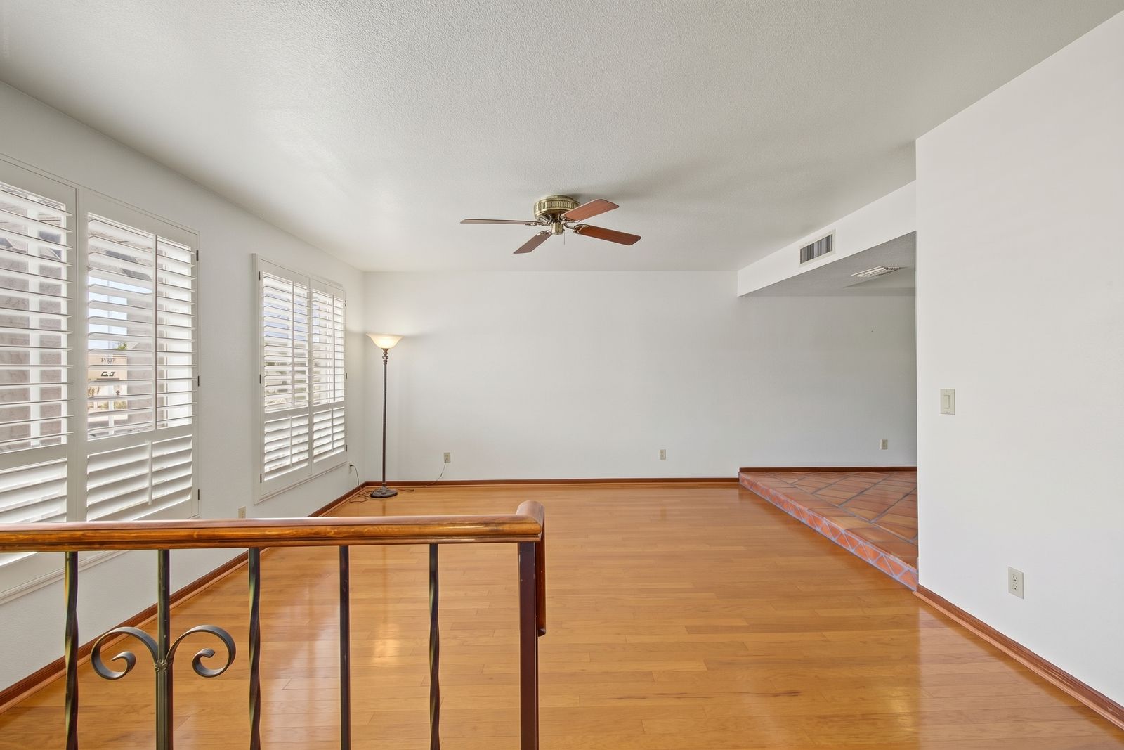 Living room seen from the entry railing, with a floor lamp