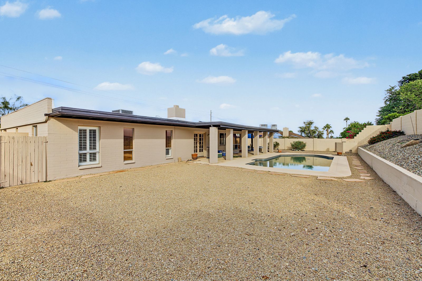 Backyard with gravel landscaping, covered patio and pool